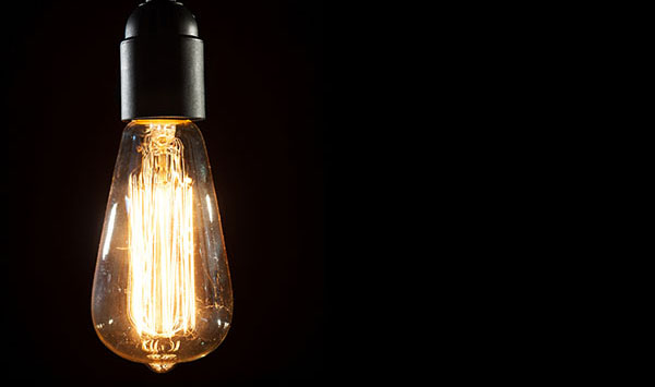 A lit Edison light bulb against a black background